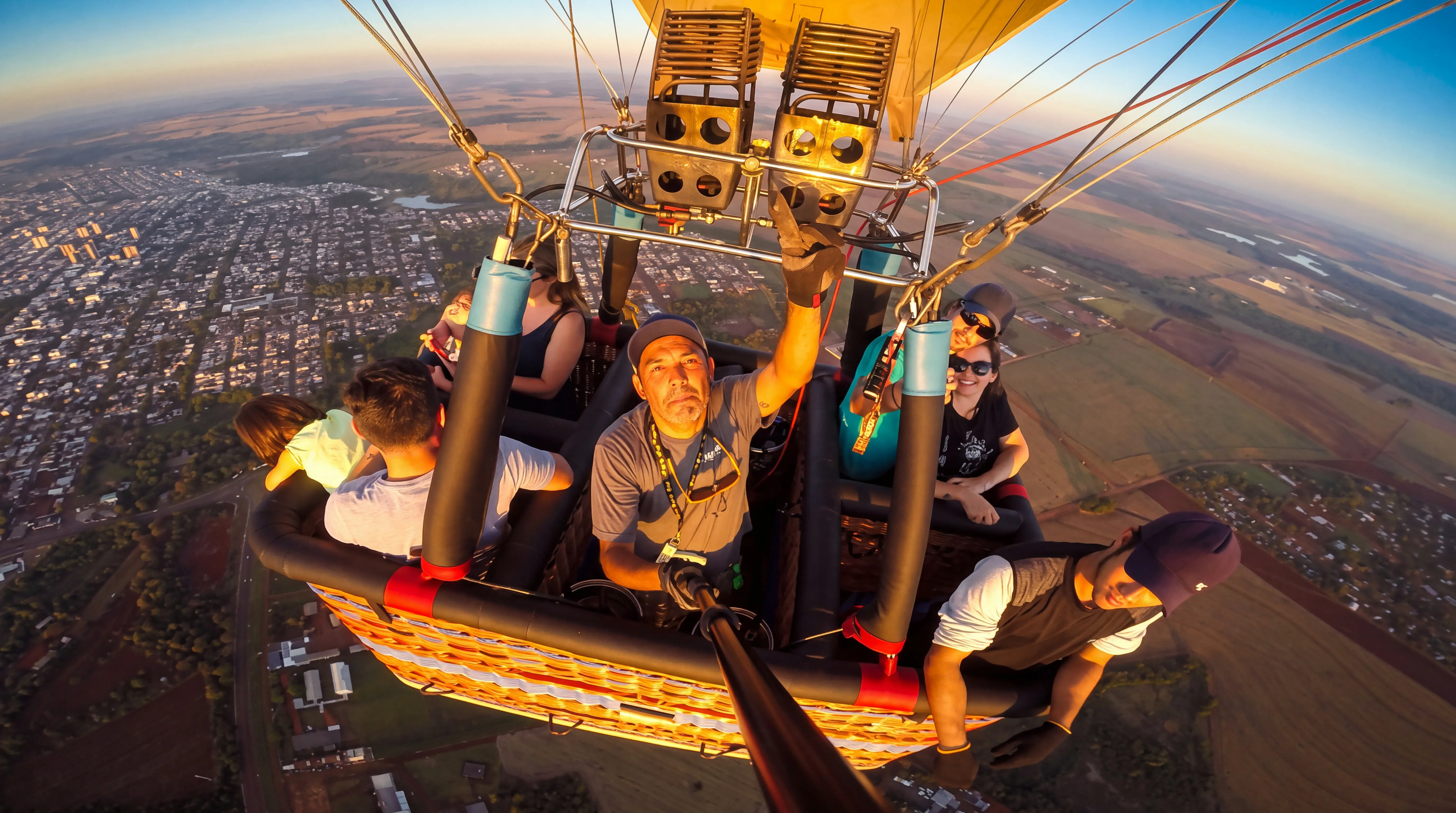 Passageiros no cesto do balão vistos de cima, com a cidade lá embaixo